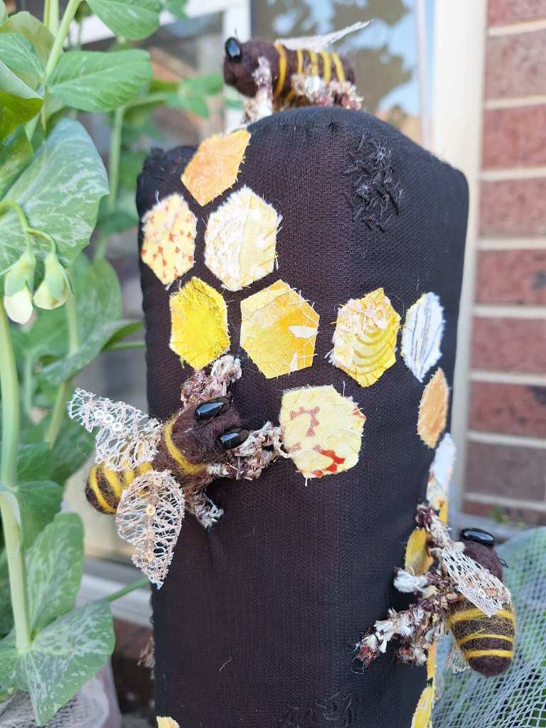 3d textile sculpture with appliqued fabric honeycomb design. Needle felted 3d bees with free machine embroidered lace wings and bead eyes.