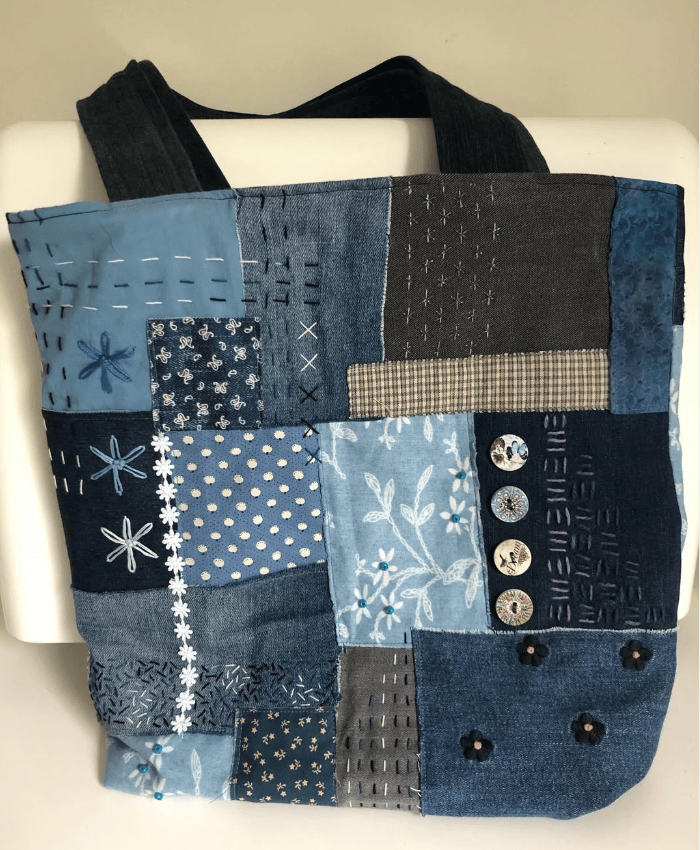 Patchwork tote bag made from of blue fabric scraps, decorated with buttons beads and embroidery.