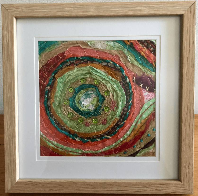 Framed circular swirl pattern embellished with beads, sequins and hand embroidered stitches.